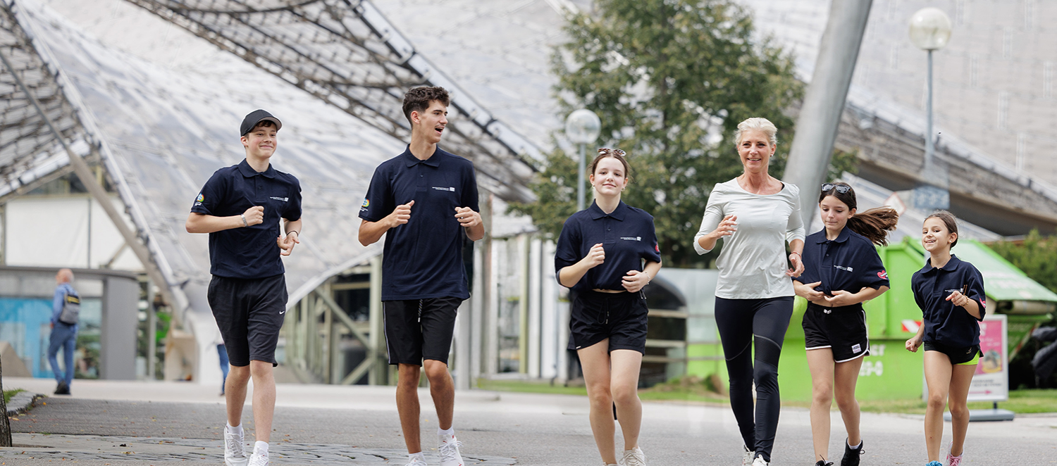 Bayerns Sozial- und Inklusionsministerin Ulrike Scharf beim Joggen mit jungen Leuten durch den Olympiapark.  Fotoquelle: StMAS/Schäffler