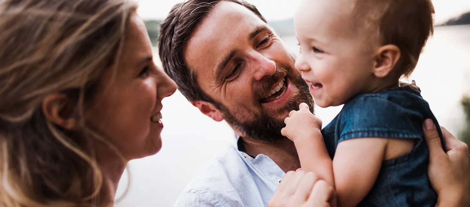 Mutter und Vater mit Kleinkind lachen zusammen