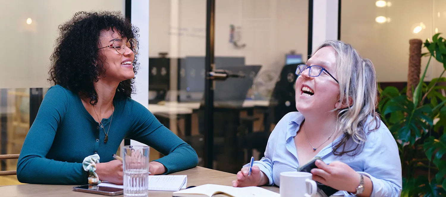 Zwei Frauen lachen miteinander eine davon hat eine Behinderung