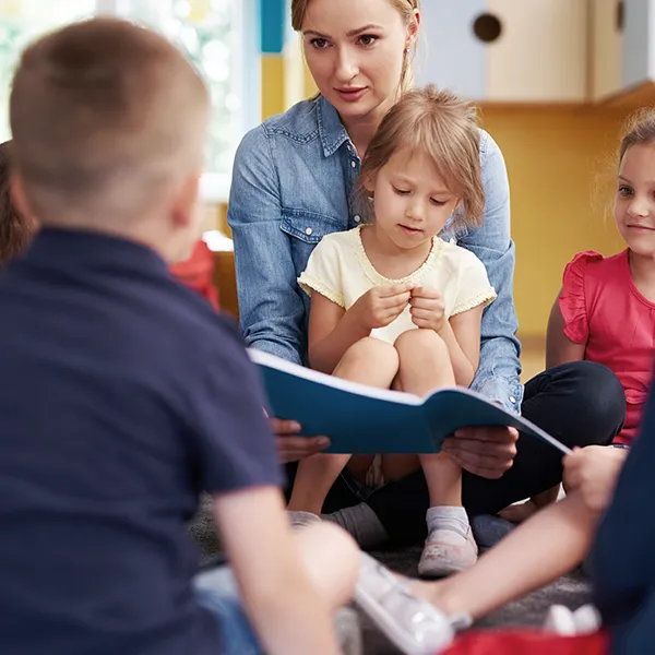 Erzieherin liest einer Gruppe Kinder etwas vor 