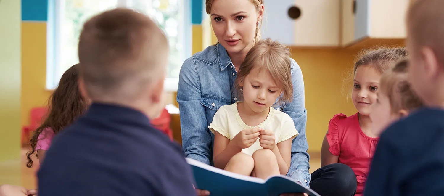 Erzieherin liest einer Gruppe Kinder etwas vor 