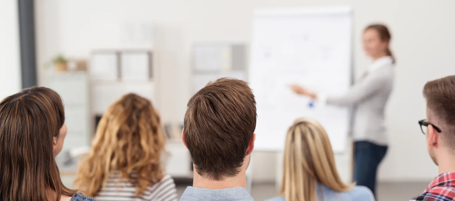 Frau hält einen Vortrag am Flipchart vor einer Gruppe