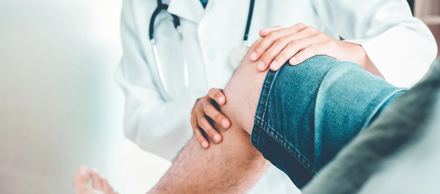 Ärztin untersucht das Knie eines Patienten 